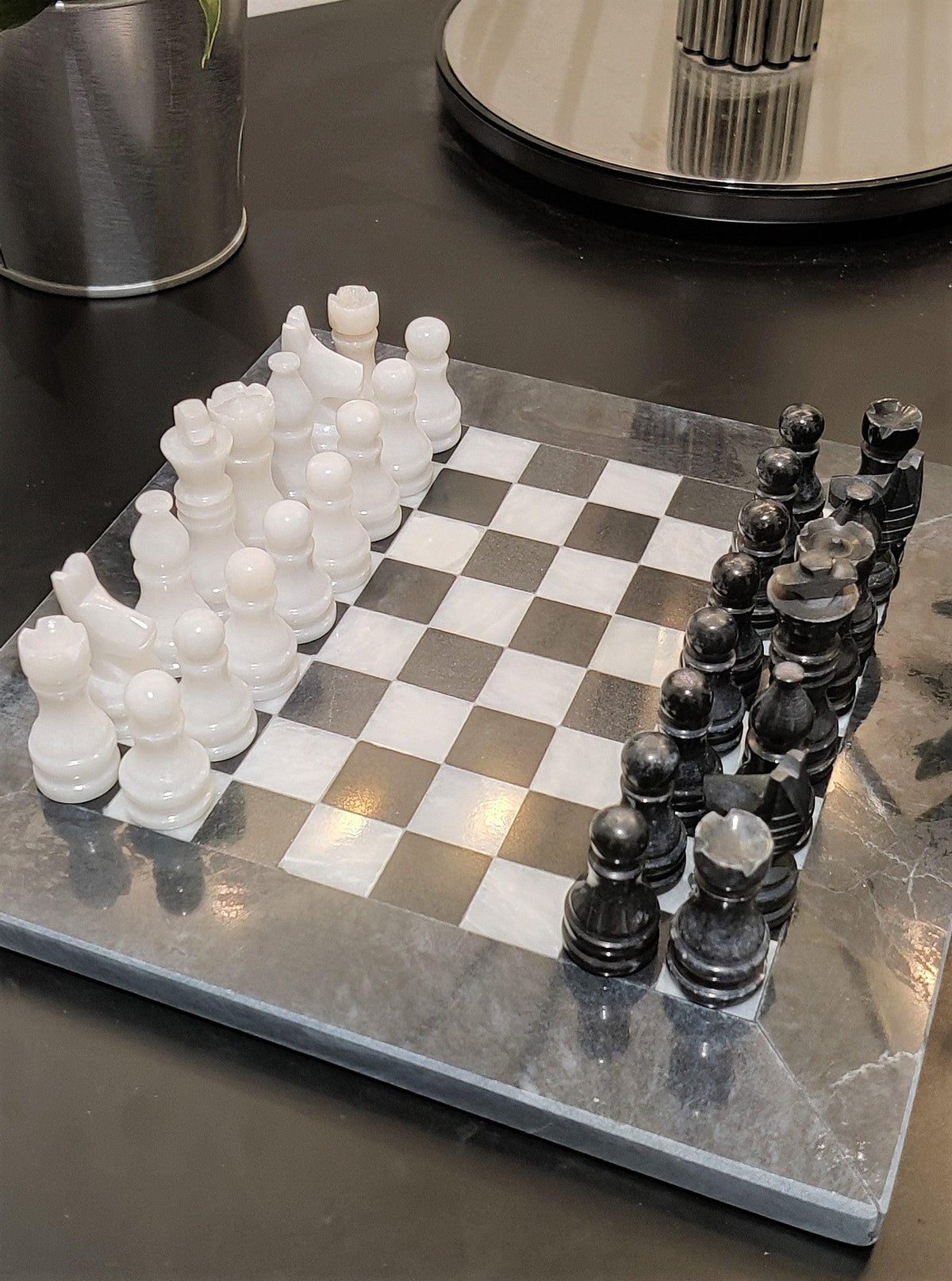 Black and white chess pieces on a grey-bordered marble board