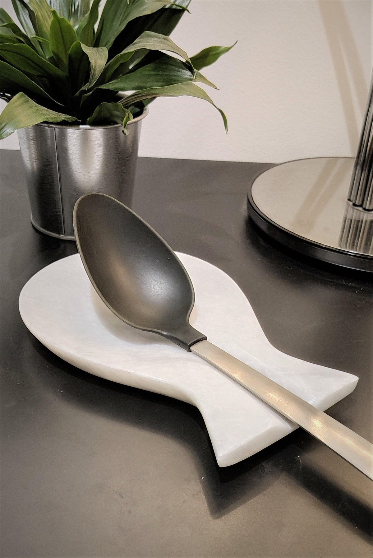 White marble spoon rest holding a black ladle
