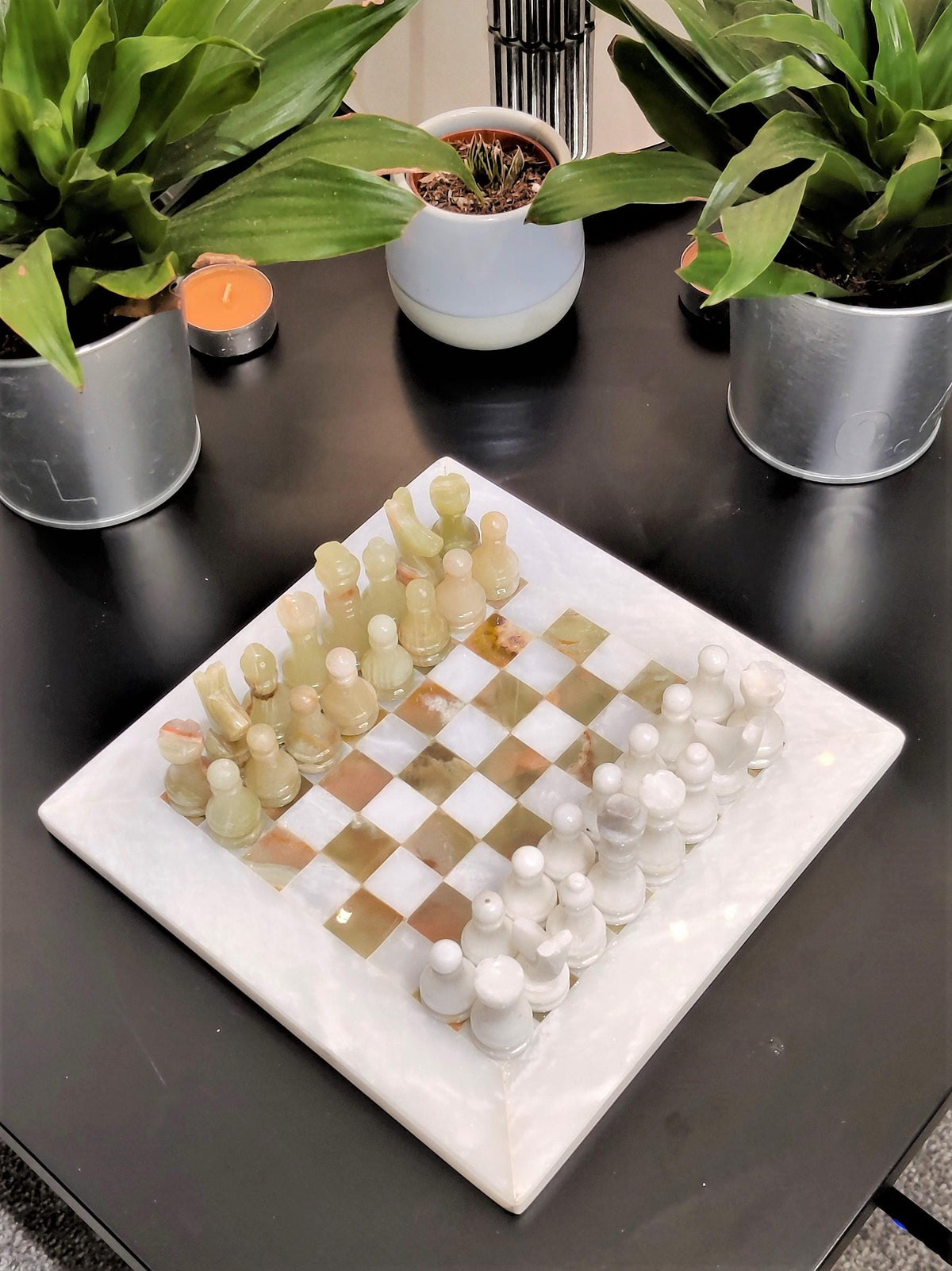 Onyx and white marble chess set with candles and plants