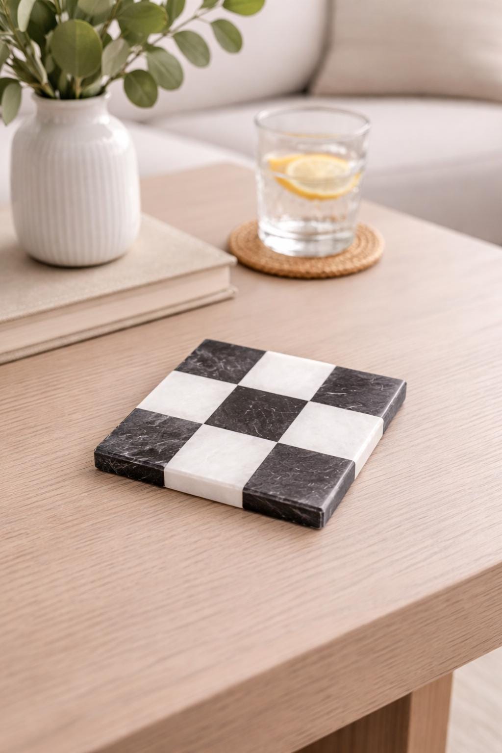 Black and white checked marble coaster with a glass of water