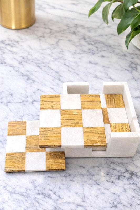 Brown and white checked marble coasters on a white marble surface