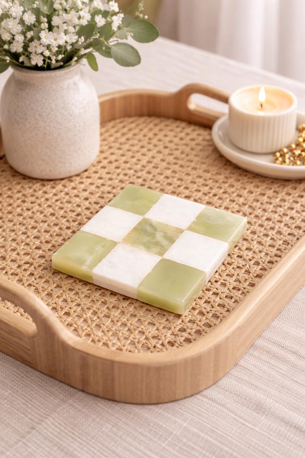 Green onyx and white checked marble coaster on a rattan tray with a candle