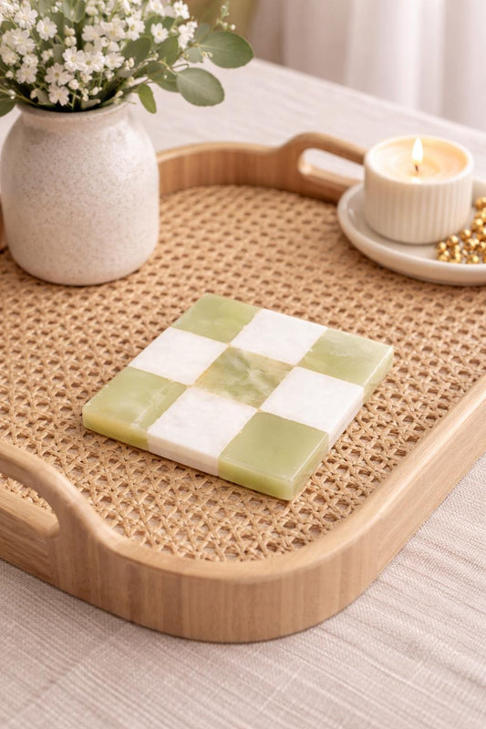 Green onyx and white checked marble coaster on a rattan tray with a candle